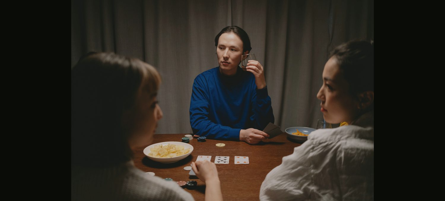 A dim, warm private card room with tea and cards on the table